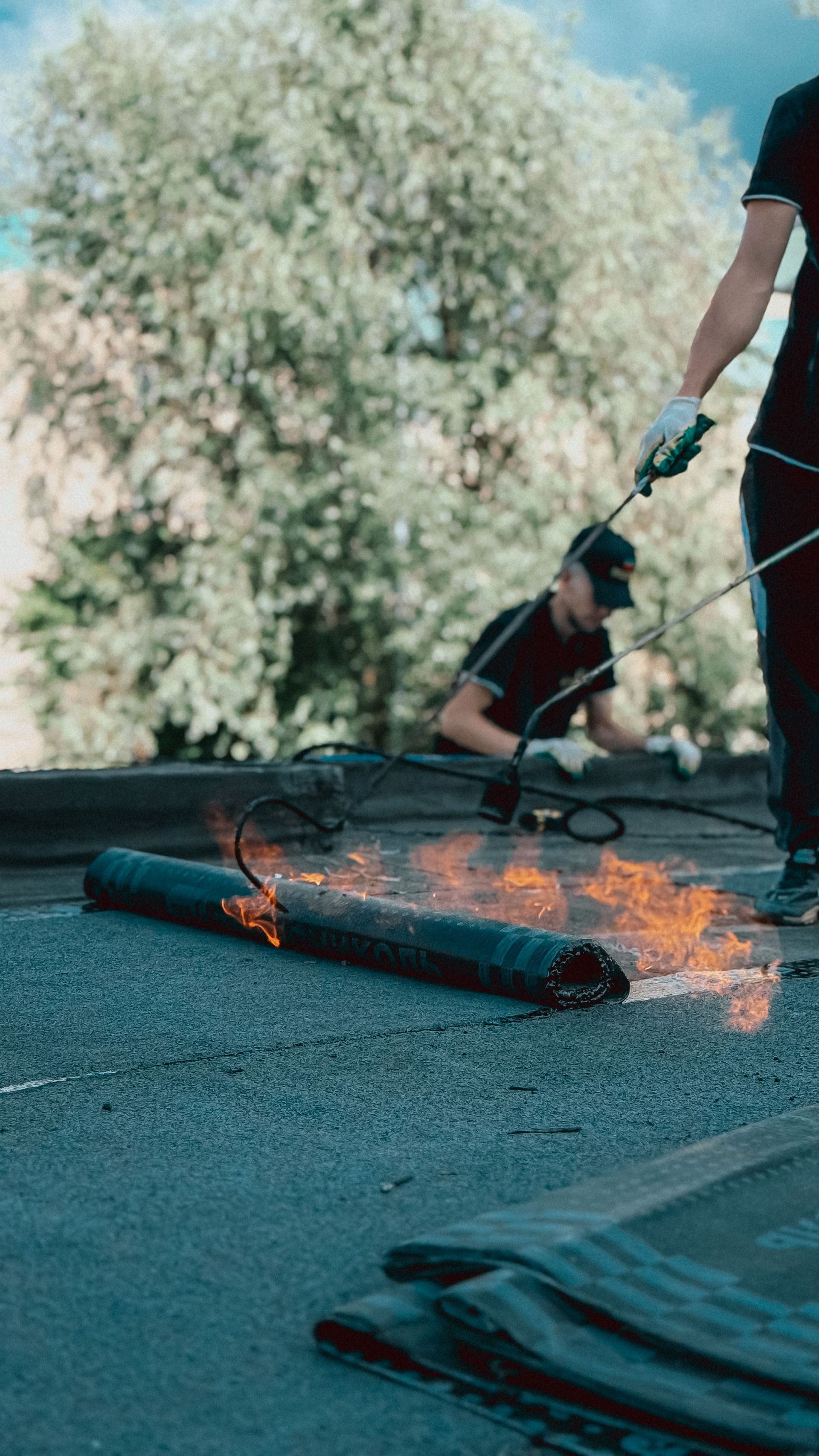 Person using a grinder on a roof, sending sparks from a metal surface.
