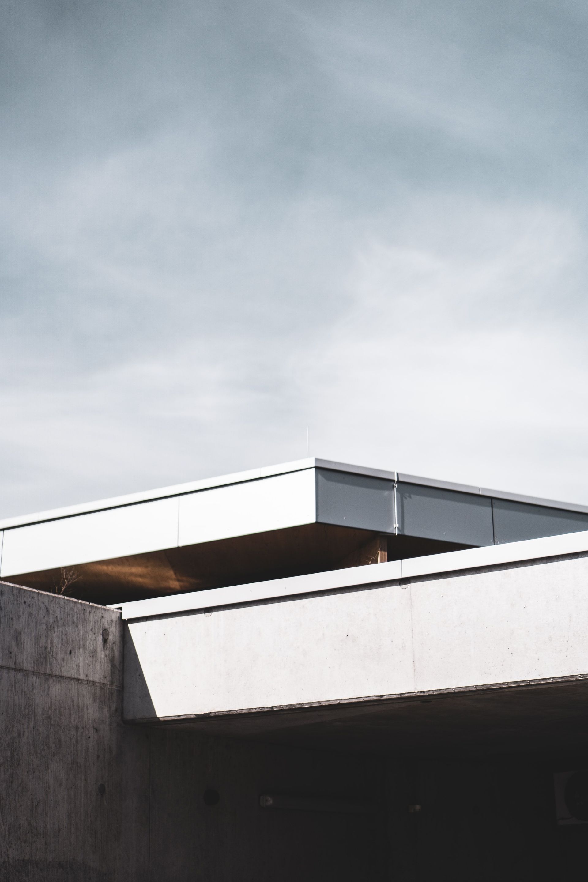 Modern building roof with white overhang against a cloudy sky