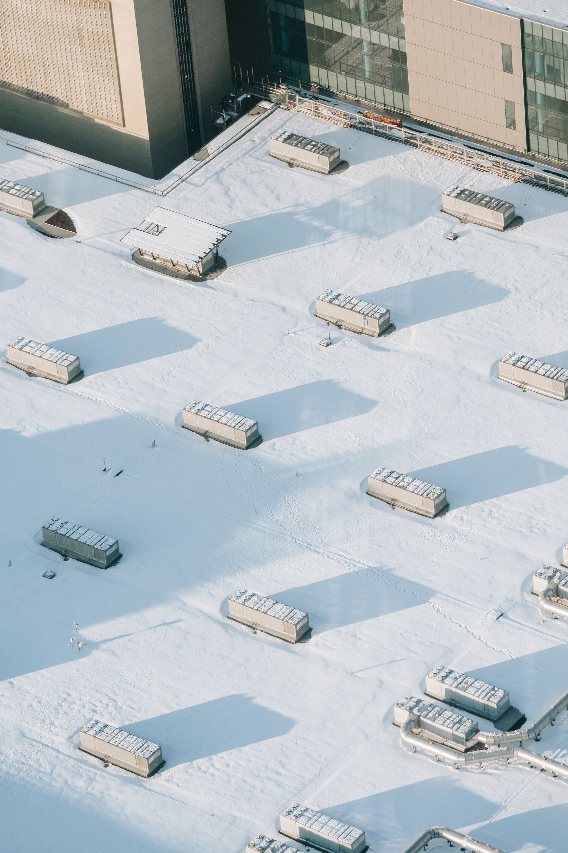 Snow-covered rooftop with multiple HVAC units and tall buildings in the background