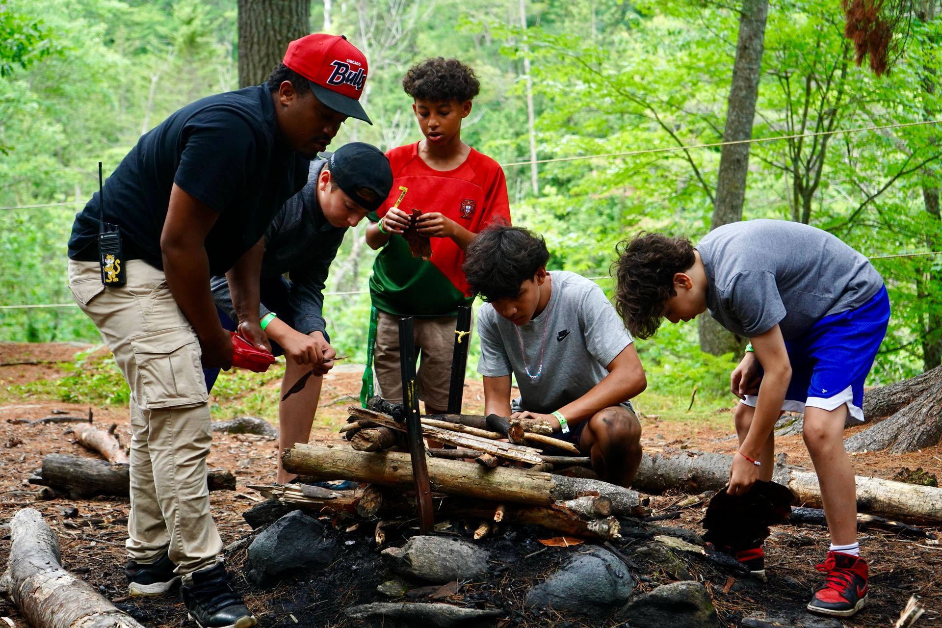 A group of people are learning how to build a camp fire.