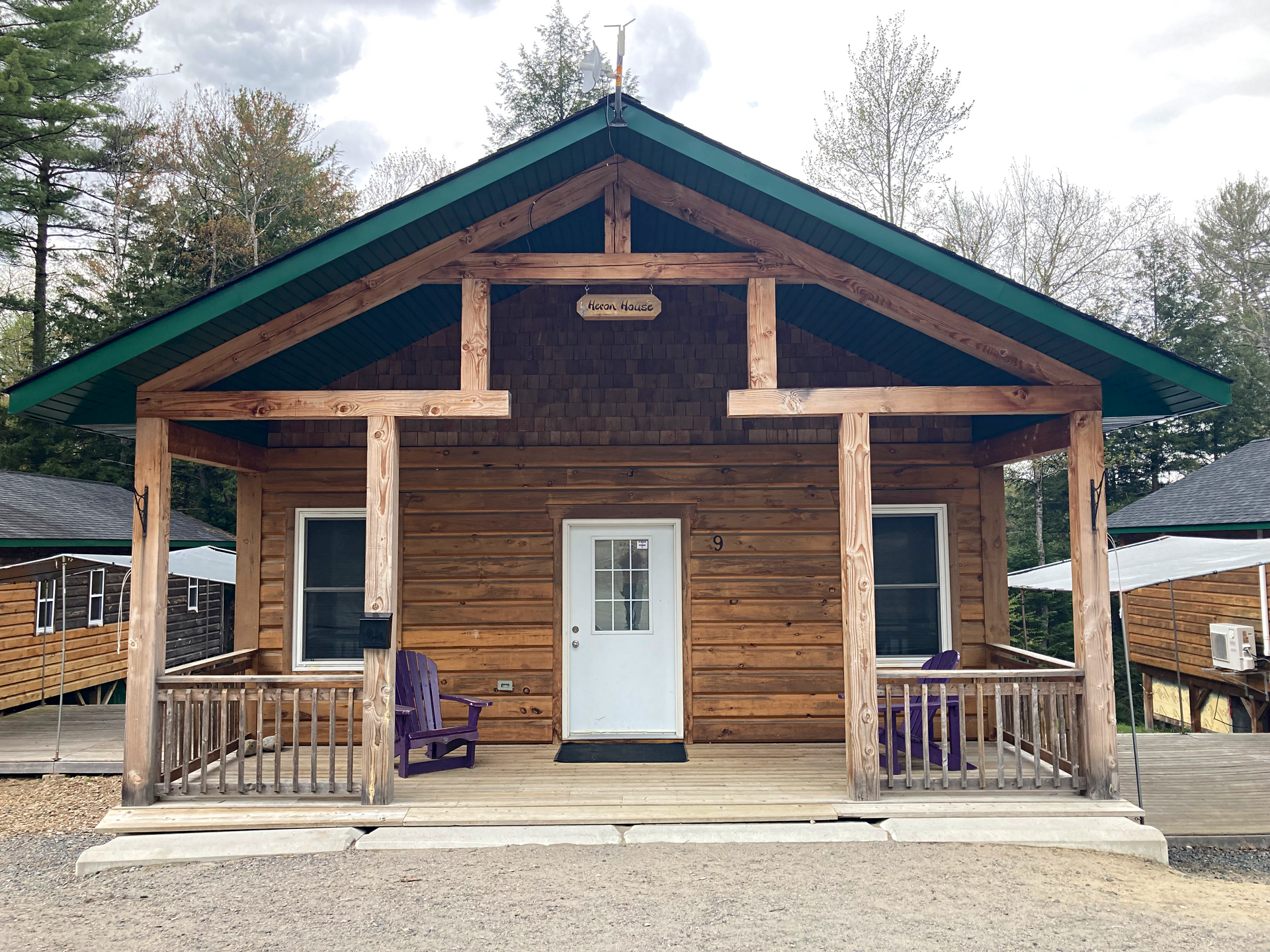 A small log cabin with a porch and purple chairs