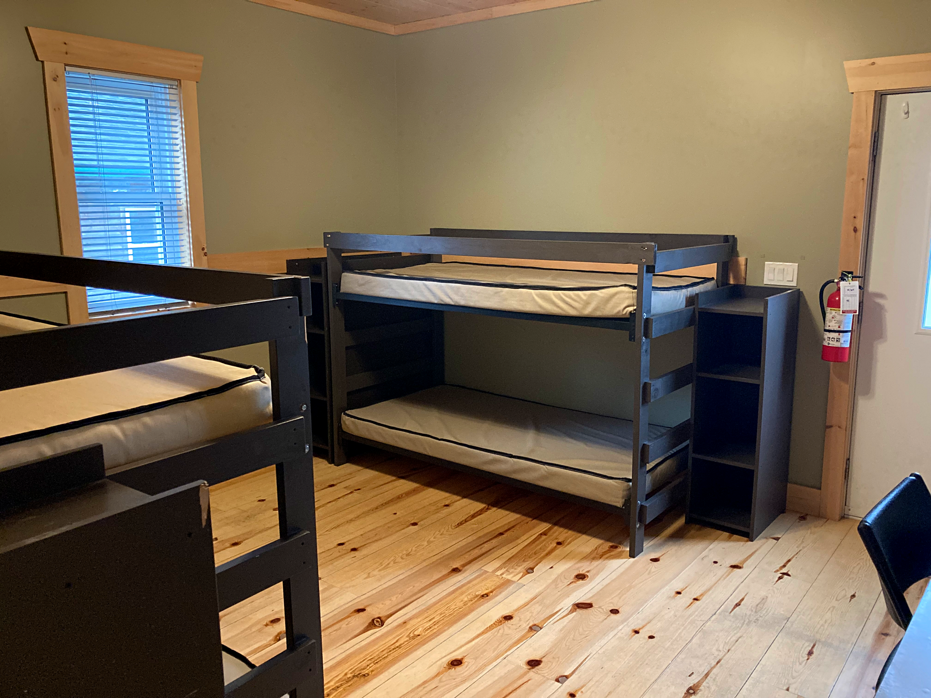 A room with three bunk beds and a fire extinguisher