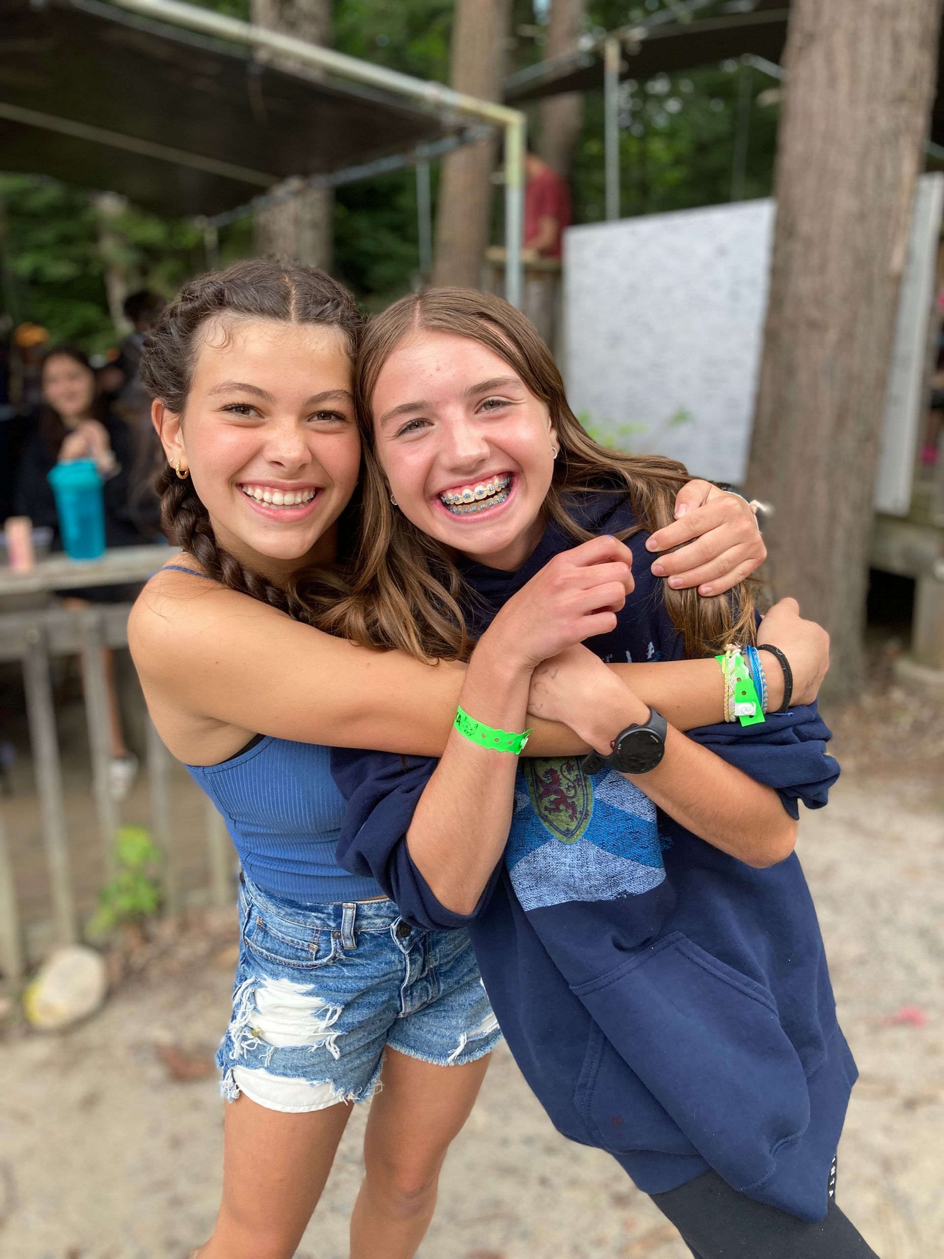 Two young girls are hugging each other and smiling for the camera.