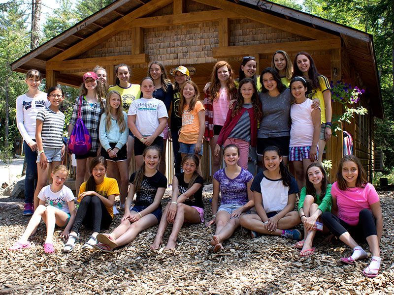 A group of young girls are posing for a picture in front of a wooden building.