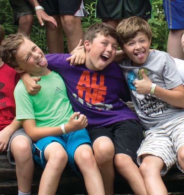 A group of young boys are posing for a picture and one of them is wearing a shirt that says all the