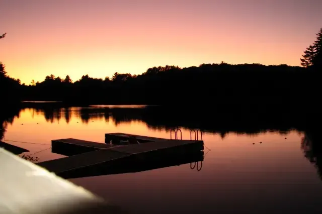A sunset over a lake with a dock in the foreground