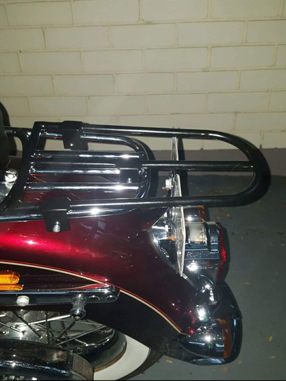A black motorcycle luggage rack attached to a red fender with chrome accents.