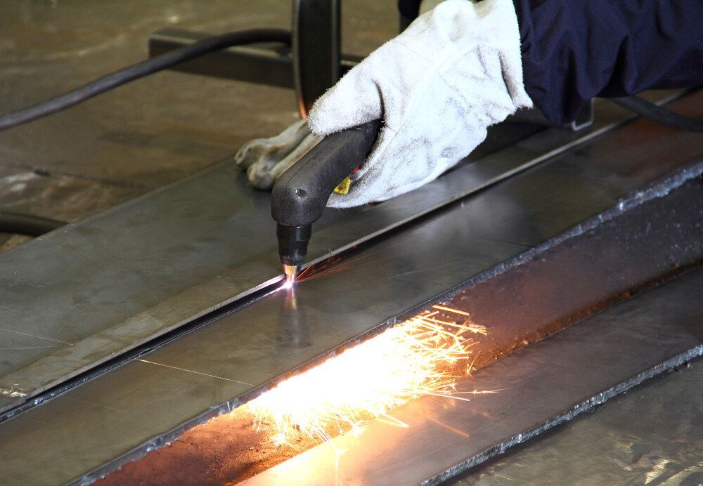 A Person Is Cutting A Piece Of Metal With A Torch — Dalrymple Sheet Metal In Mackay, QLD