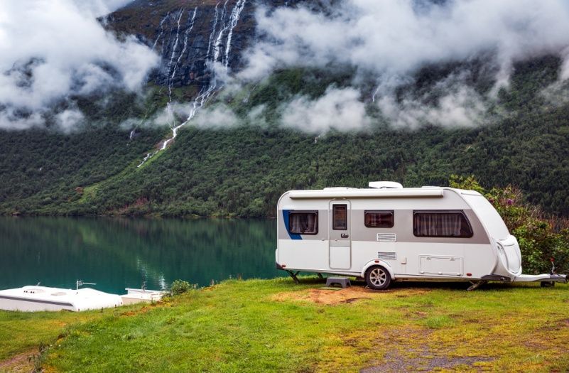 A Caravan is Parked on a Grassy Hill Next to a Lake — Chilltech Air Conditioning & Refrigeration In Gracemere, QLD