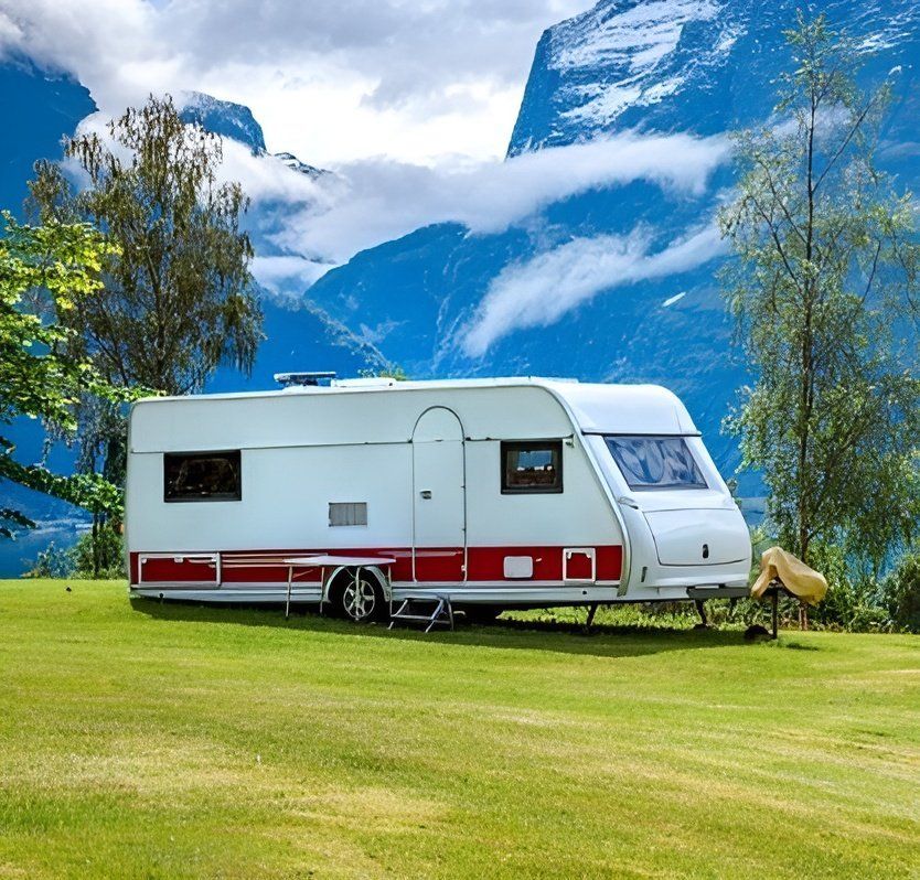A Caravan is Parked in a Grassy Field in Front of a Mountain — Chilltech Air Conditioning & Refrigeration In Gracemere, QLD
