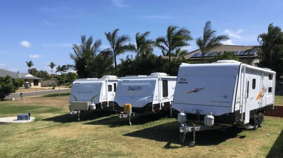 A Row of Trailers Are Parked in a Grassy Field — Chilltech Air Conditioning & Refrigeration In Rockyview, QLD
