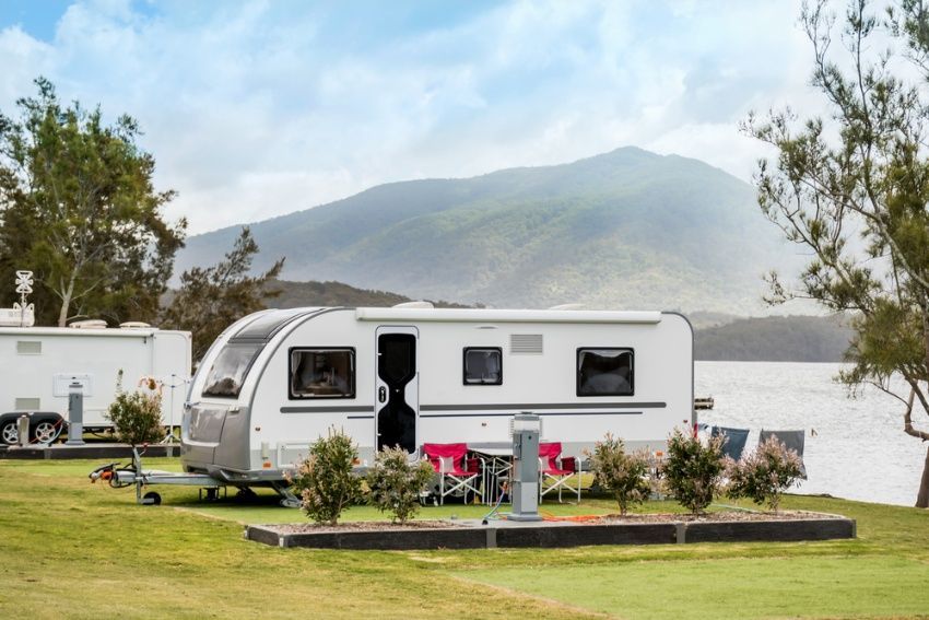 A Caravan is Parked in a Grassy Area Next to a Lake — Chilltech Air Conditioning & Refrigeration In Rockyview, QLD