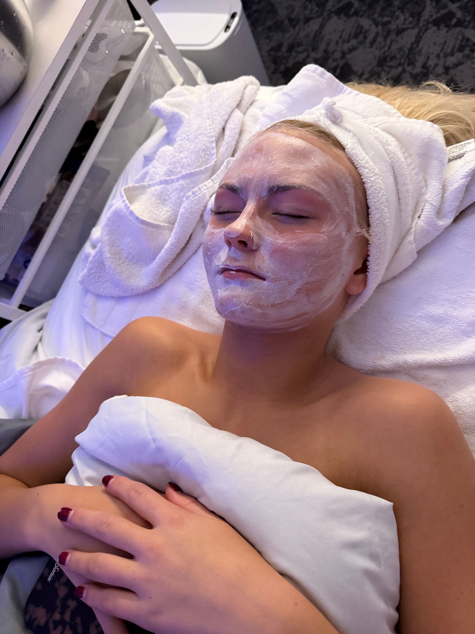 Two spa clients with facial masks reclining during a facial treatment in a bright salon