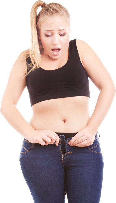 A woman in a black top and blue jeans is looking at her waist.