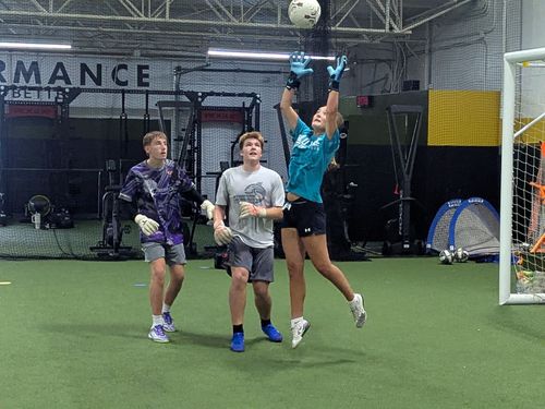 Protect Your Net - A girl and two boys playing indoor soccer, one jumping to catch a ball near the goal
