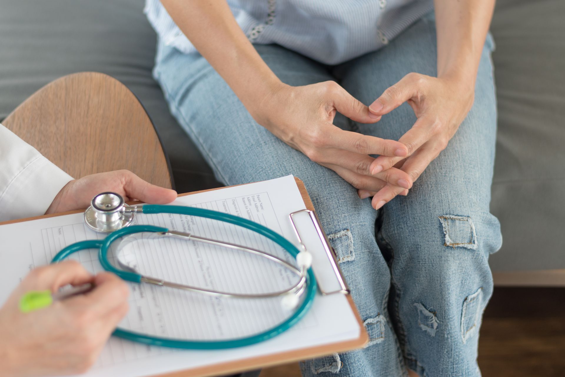 Clinician using stethoscope to examine a pregnant patient’s abdomen during checkup.
