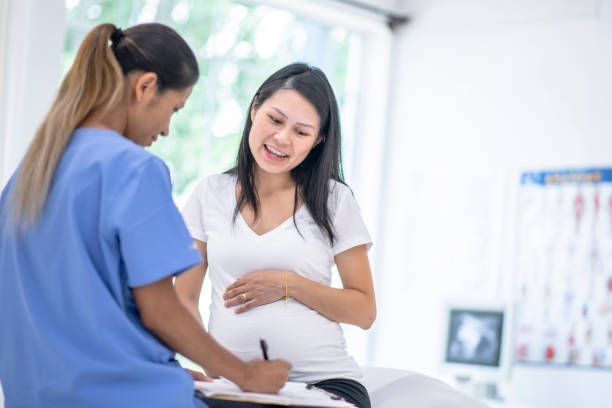 A nurse is talking to a pregnant woman in a hospital room.