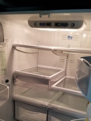The inside of an empty refrigerator with a light on.