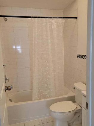 A bathroom with a toilet , bathtub and shower.