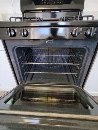 A black stove with the door open in a kitchen.