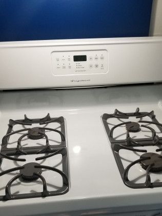 A white gas stove with four burners and a digital display.