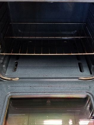 The inside of an empty oven with a glass door and racks.