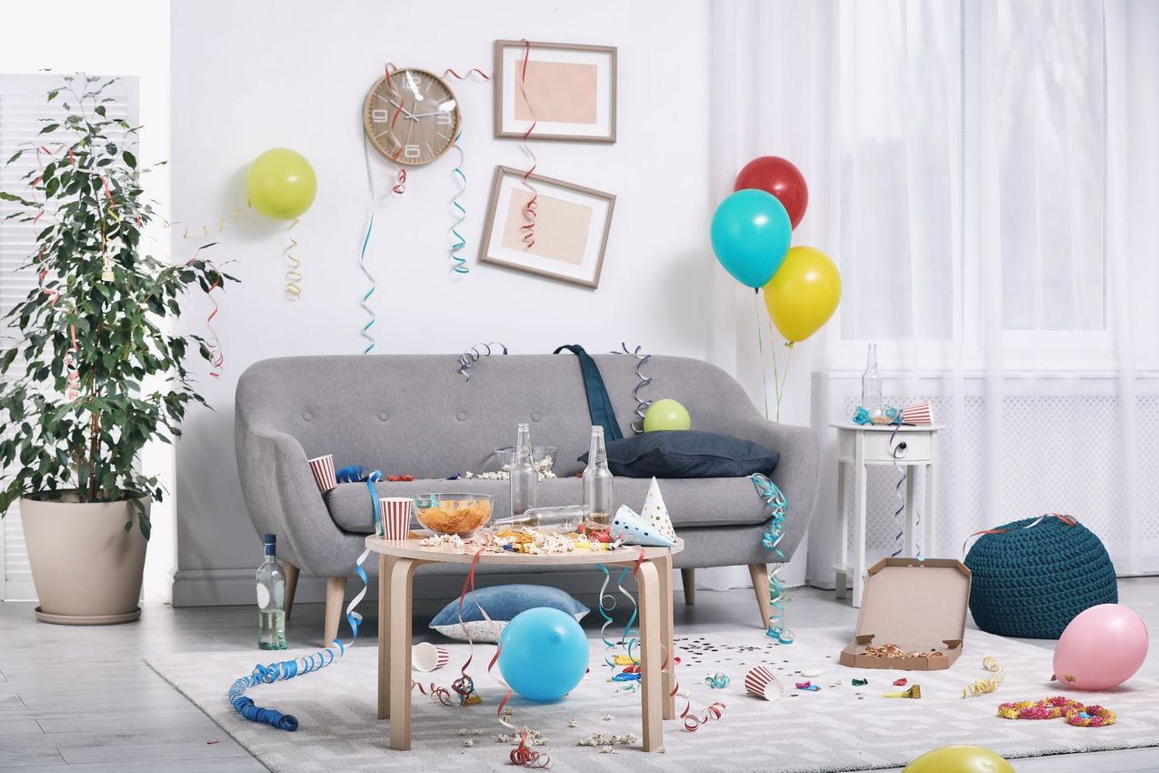 A living room with a couch , table , balloons and confetti.