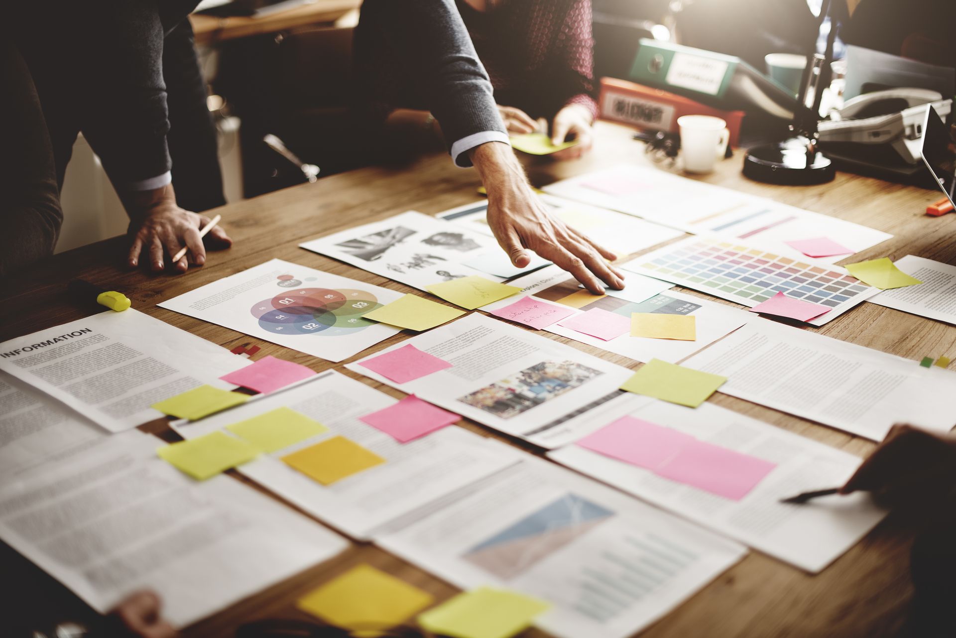 Hands organizing colorful sticky notes and papers on a worktable during a planning session
