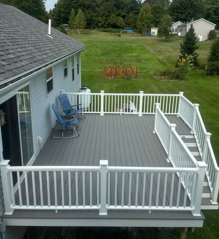 A deck with a white railing and chairs on it