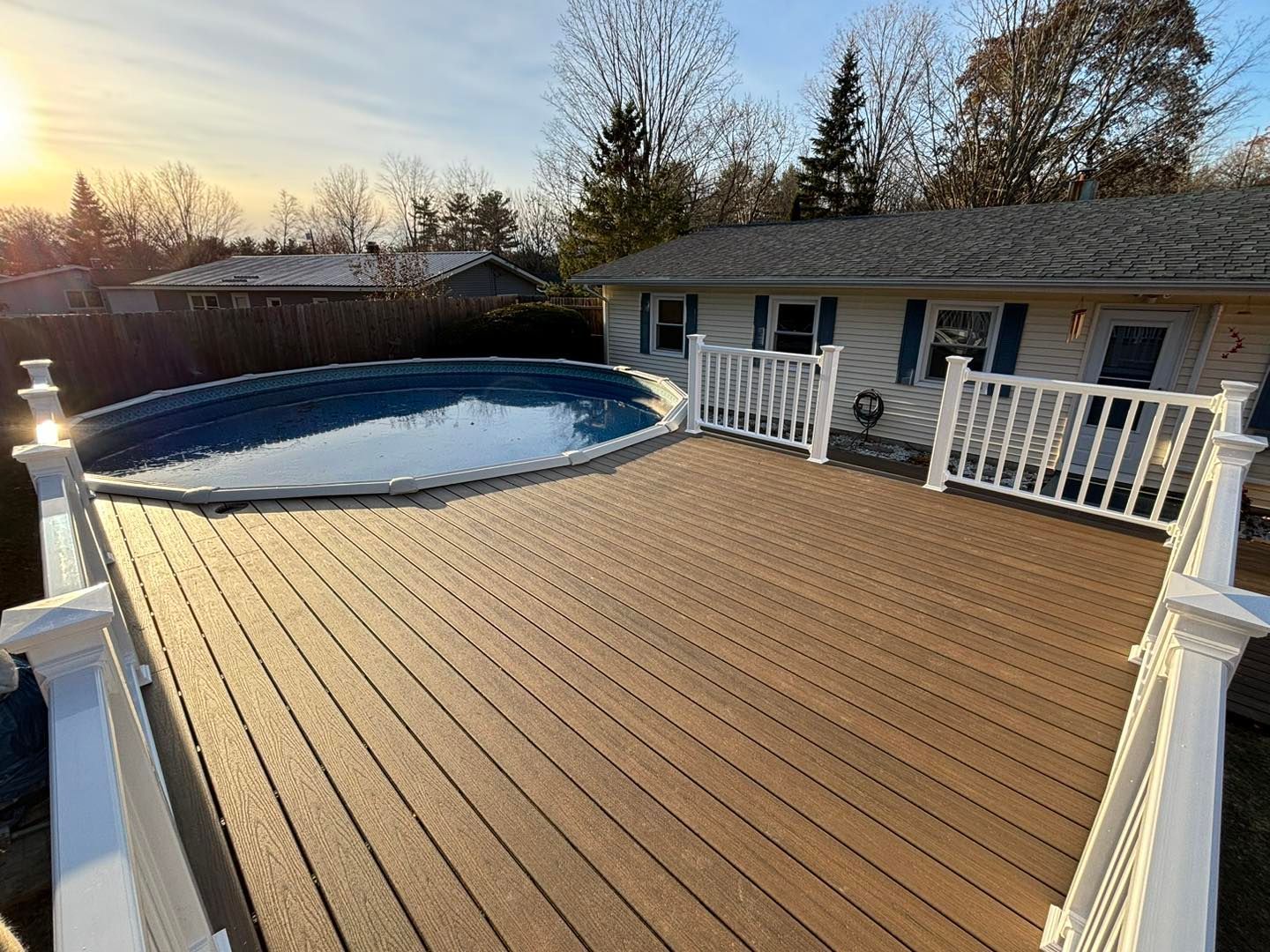 A large deck with a pool in the backyard of a house.