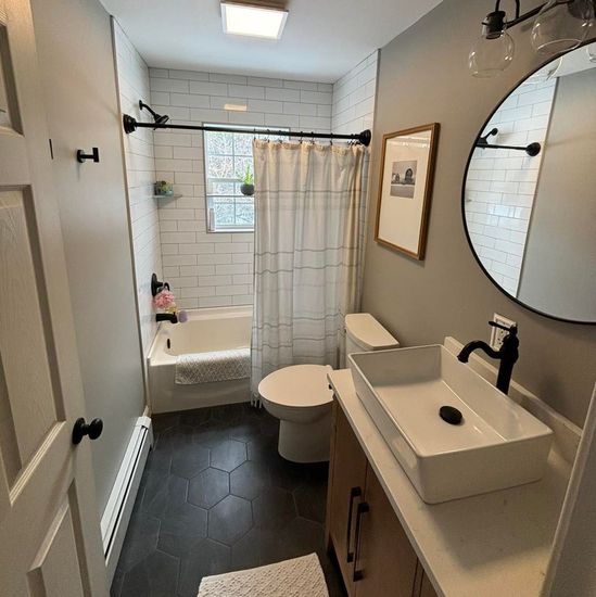 A bathroom with a sink , toilet , tub and mirror.