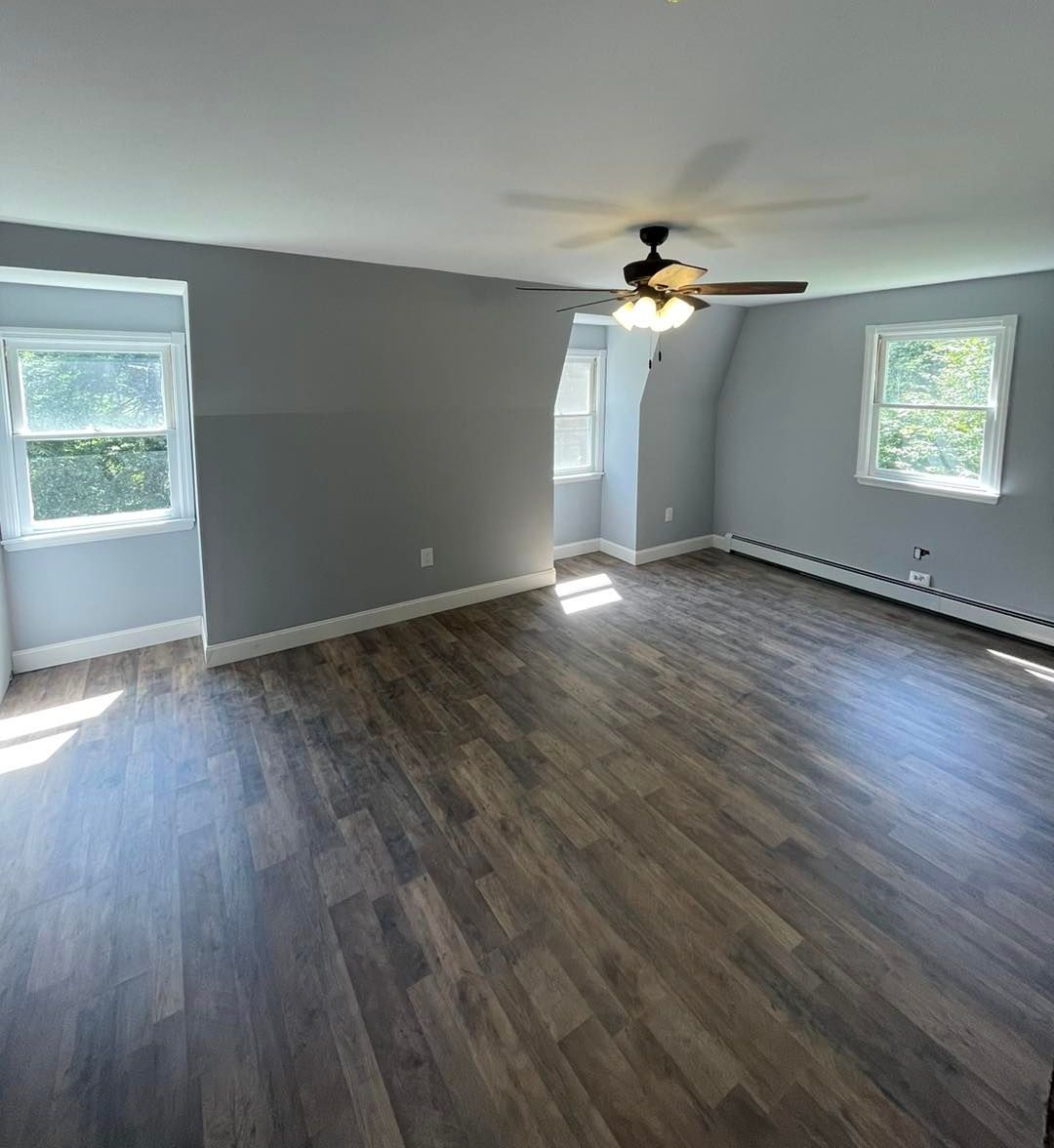 An empty living room with hardwood floors and a ceiling fan.