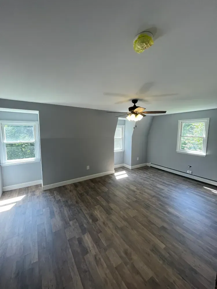 An empty living room with hardwood floors and a ceiling fan.