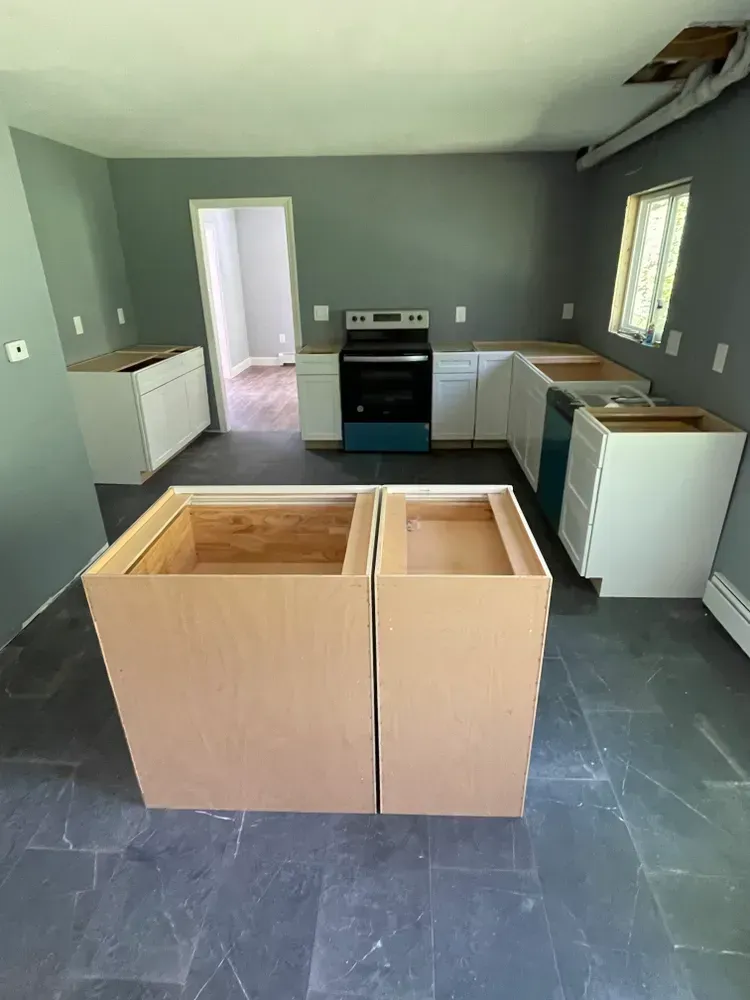 A kitchen with a stove , sink , and cabinets being built.