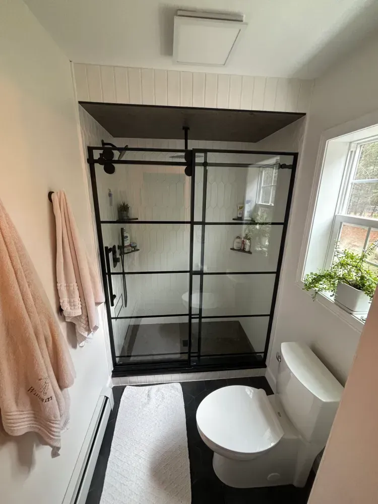 A bathroom with a toilet , shower and window.