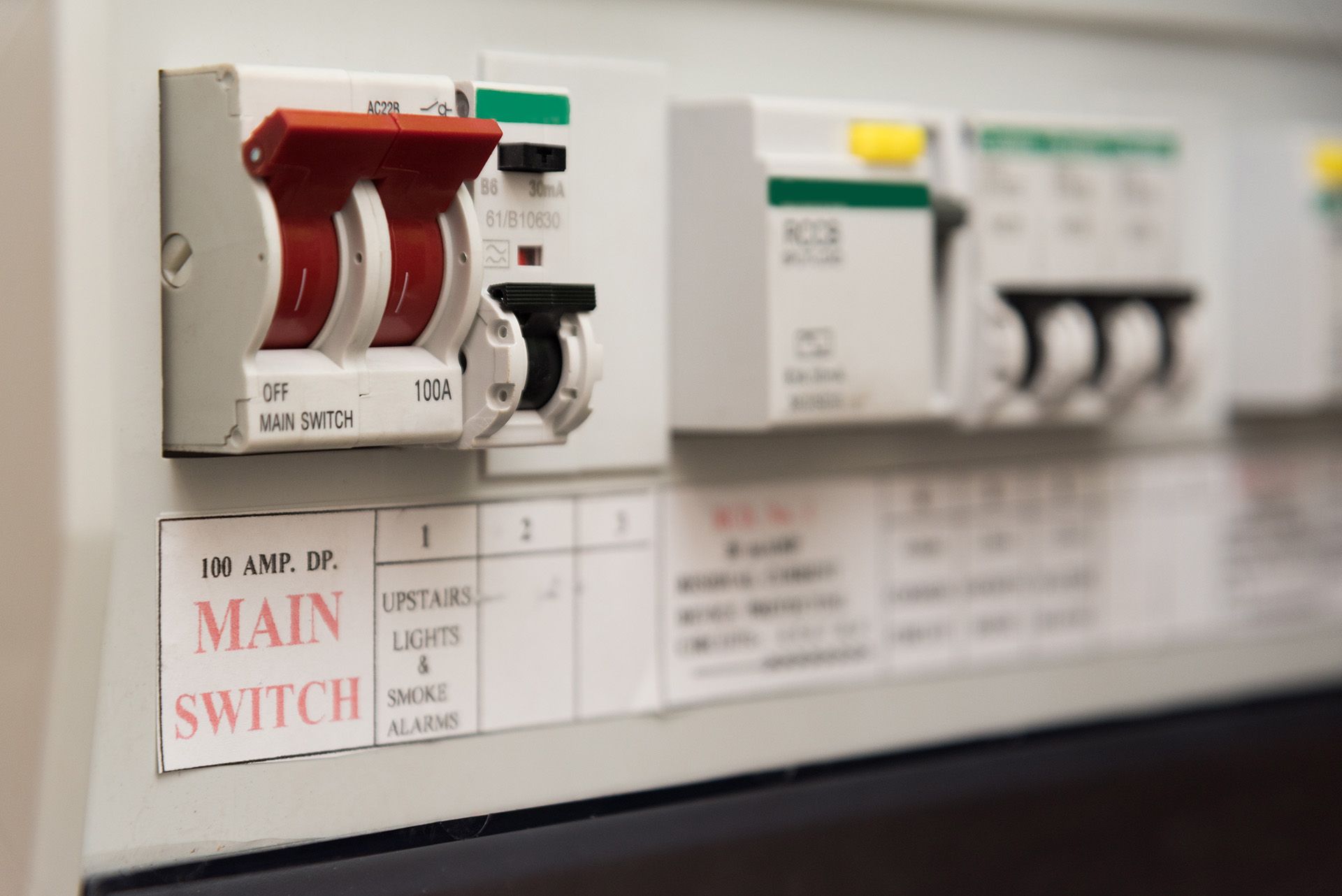 Row of electrical circuit breakers in a utility panel, including a red main switch.