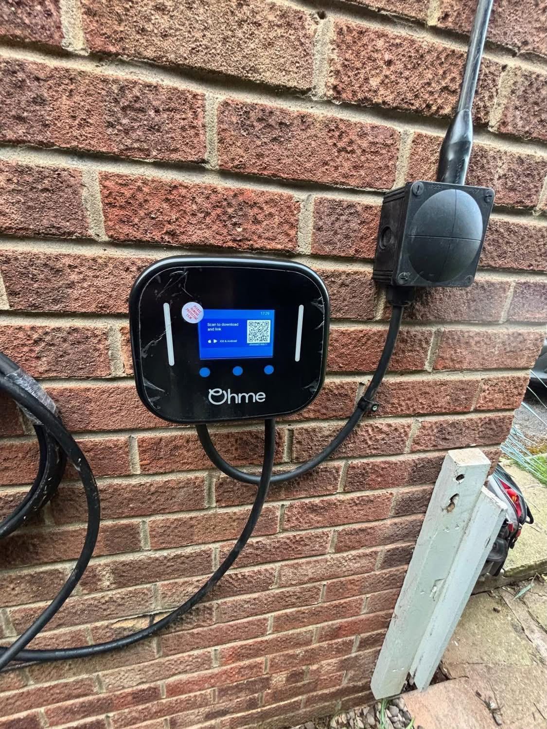 Hand plugging an EV charger into a white electric car at a charging station