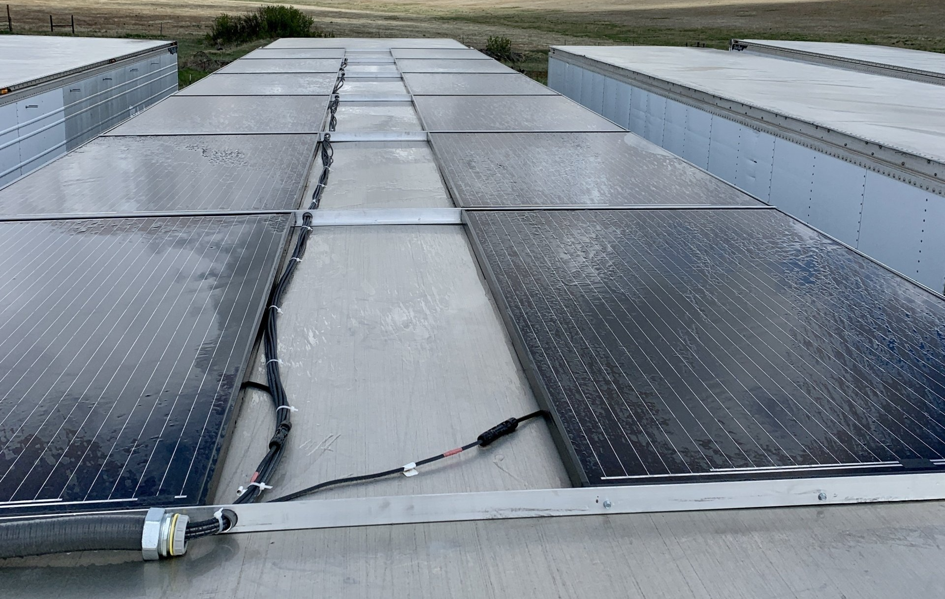 Damaged rooftop with cracked white membrane and dark solar panels on both sides