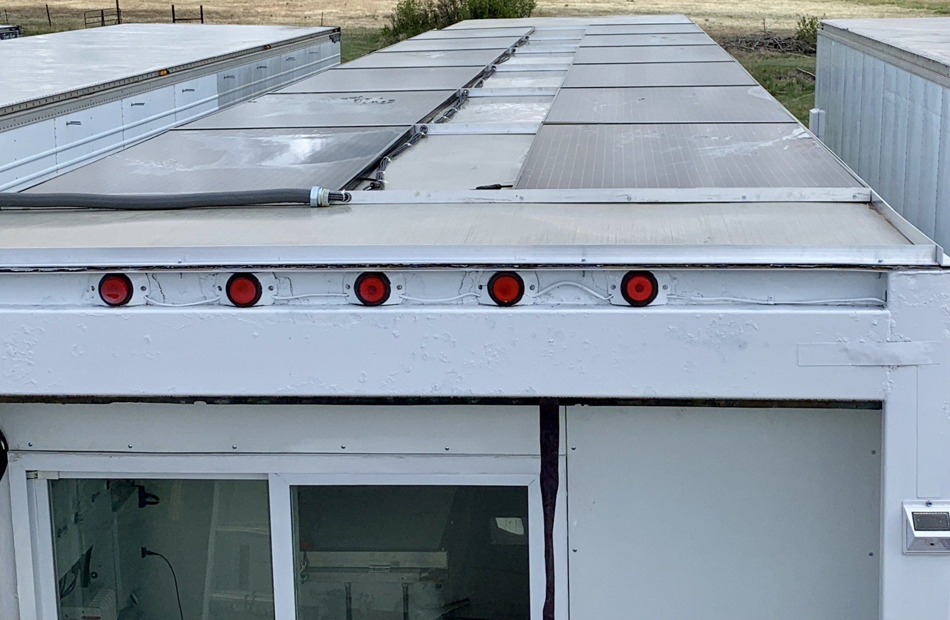 White building roof with gray metal panels and red marker lights above windows