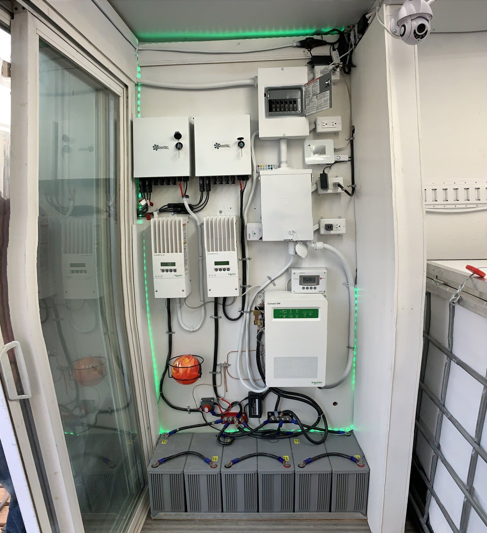 Wall-mounted electrical control panel with wiring, meters, and devices inside a cabinet room