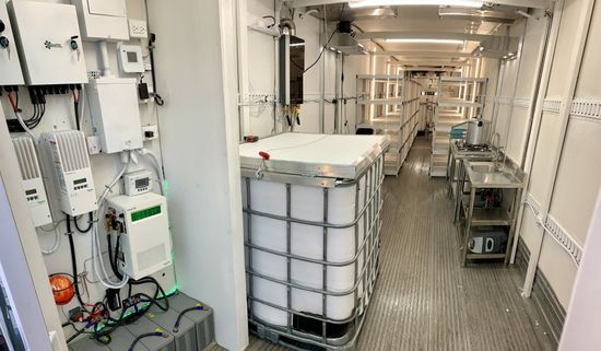 Narrow industrial corridor with white equipment tanks and metal flooring inside a ship or facility.