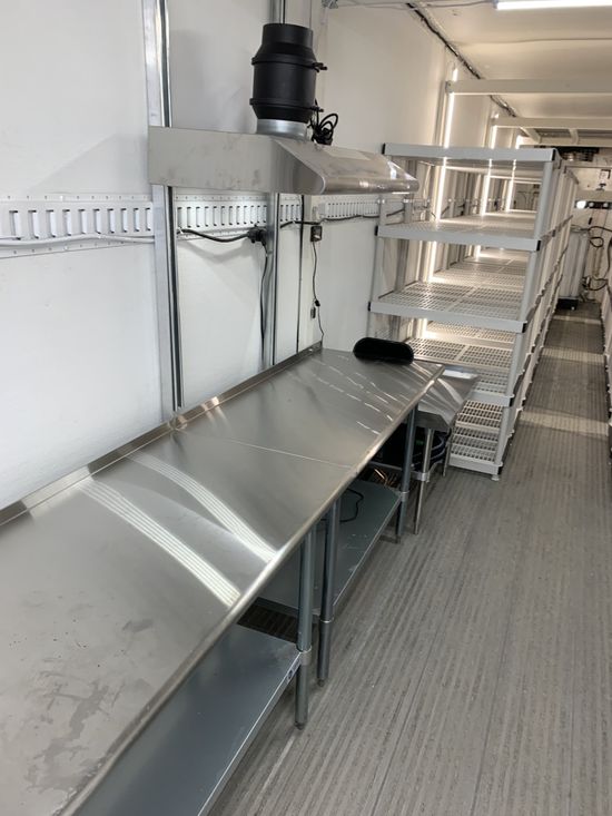 Metal workbench and shelves in a clean industrial room with stainless steel counters and a grated floor