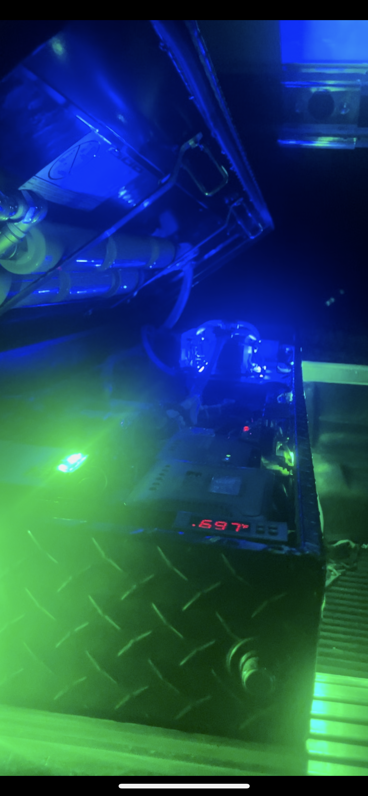 Blue and green-lit computer case with illuminated components and a diamond-plate surface below