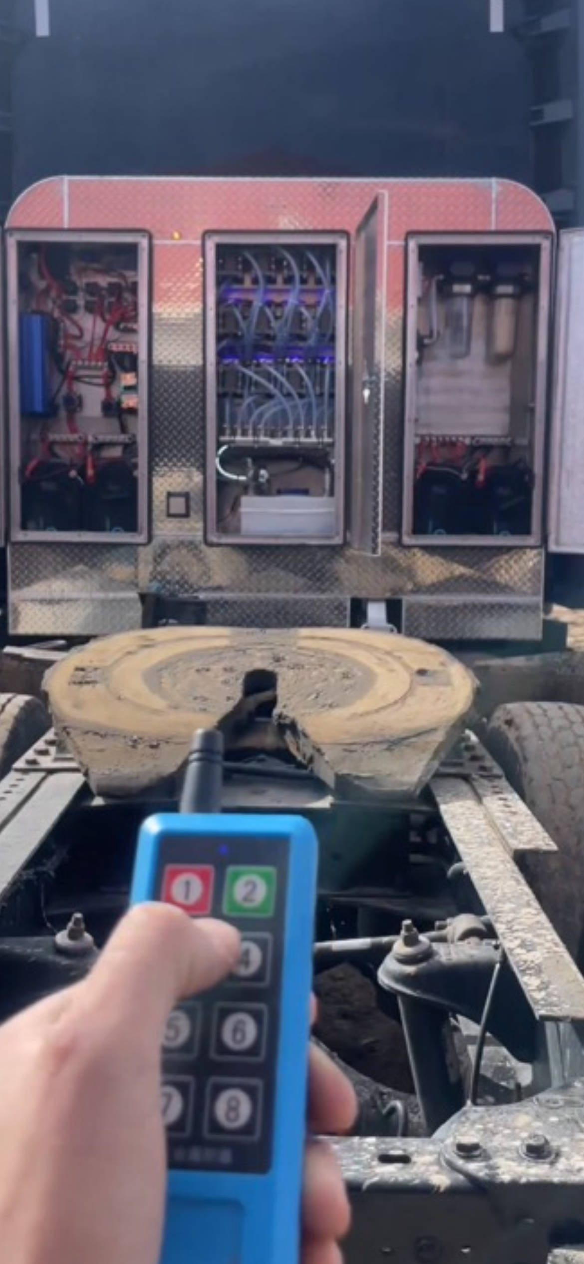 Handheld remote pointed at a cigarette vending machine with visible product rows and a large circular tray below