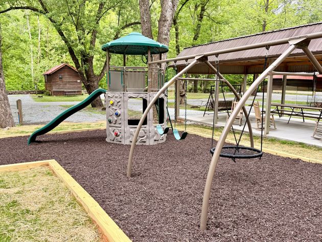 Rustic wooden cabin with porch in a wooded area.
