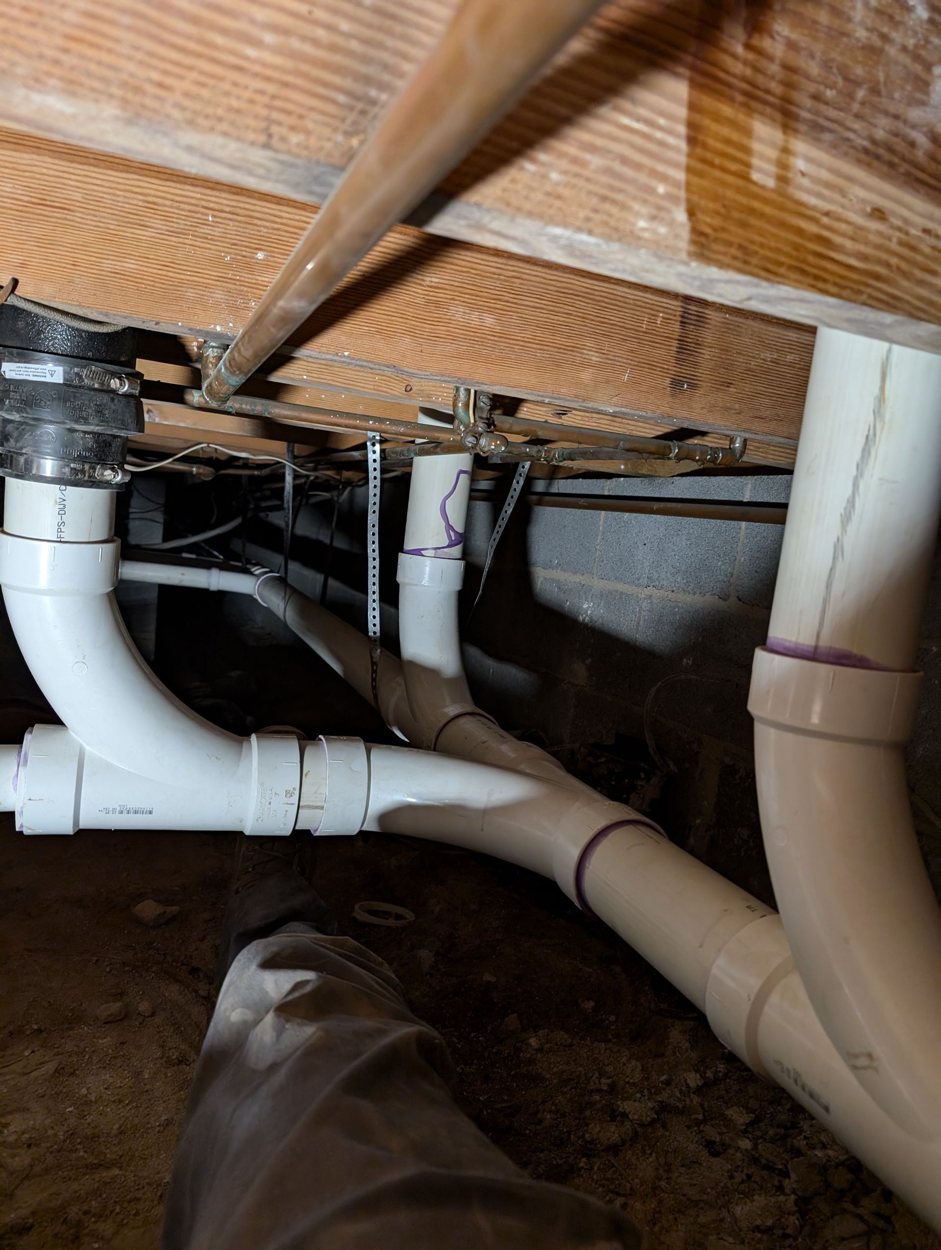 Under-floor plumbing pipes and ducts in a crawl space beneath wooden floor joists Under-floor plumbing pipes and ducts in a crawl space beneath wooden floor joists