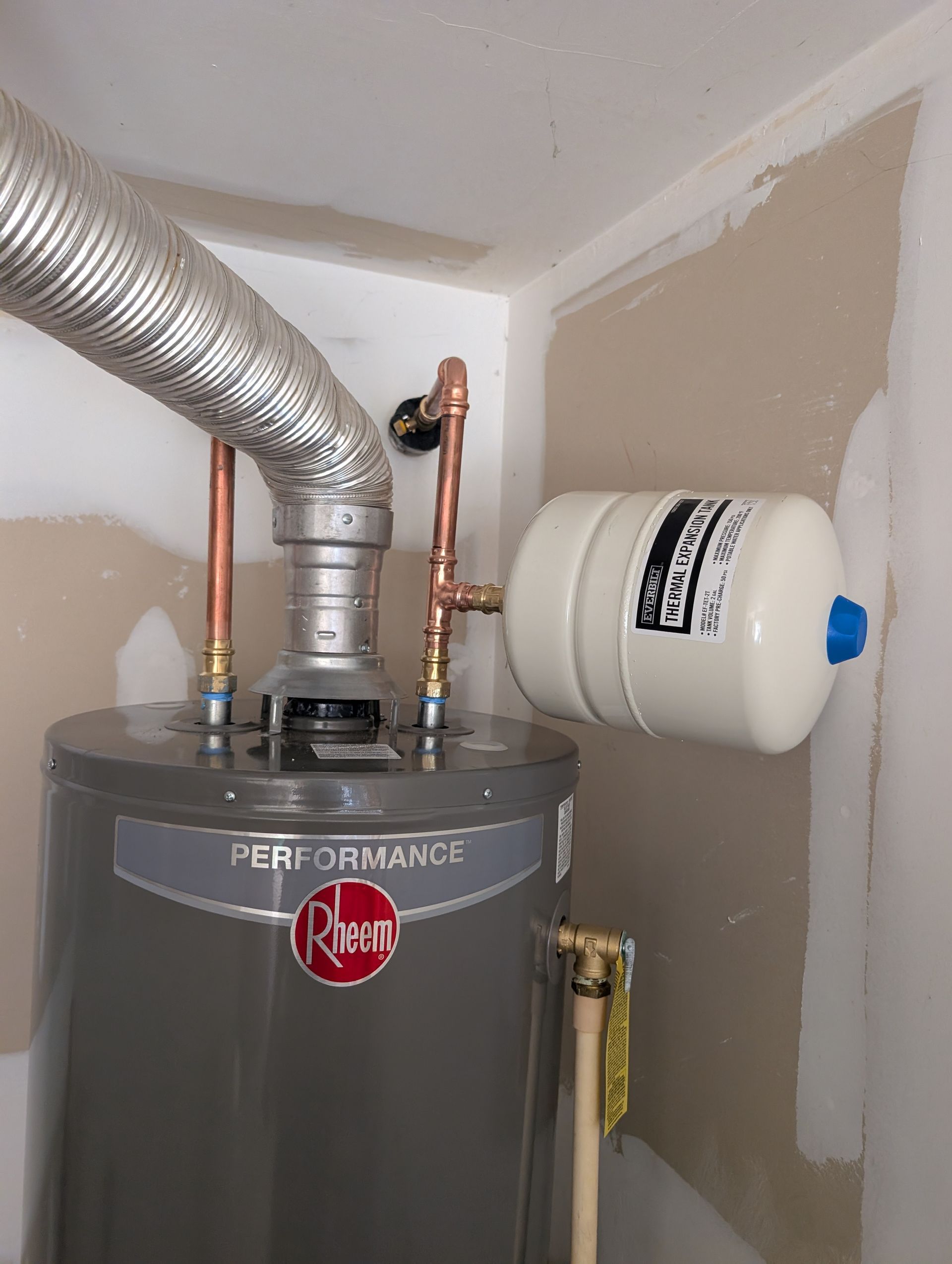 Water heater with vent pipe and expansion tank in a utility room. Water heater with vent pipe and expansion tank in a utility room.