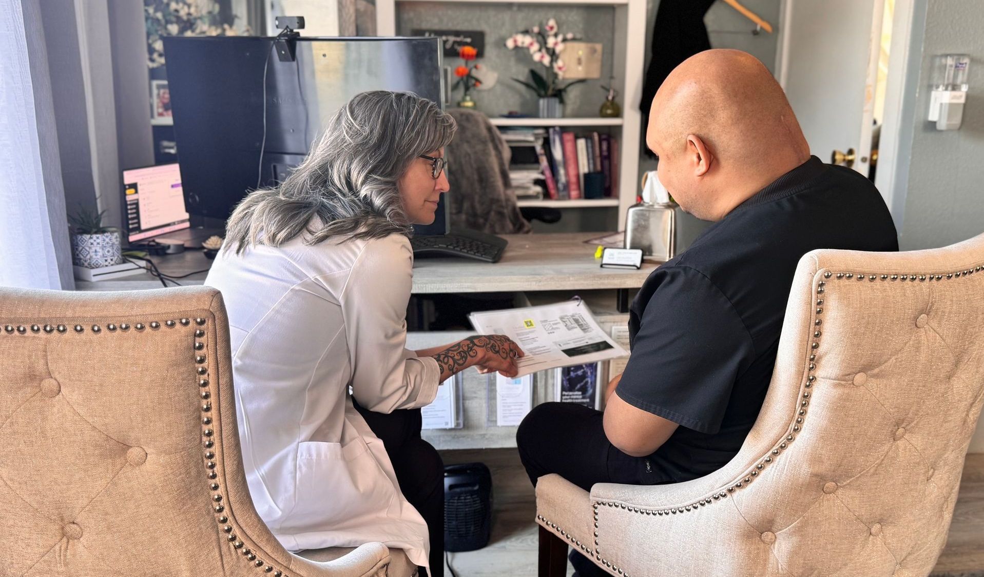 Two people sit at a table reviewing documents in a living room.