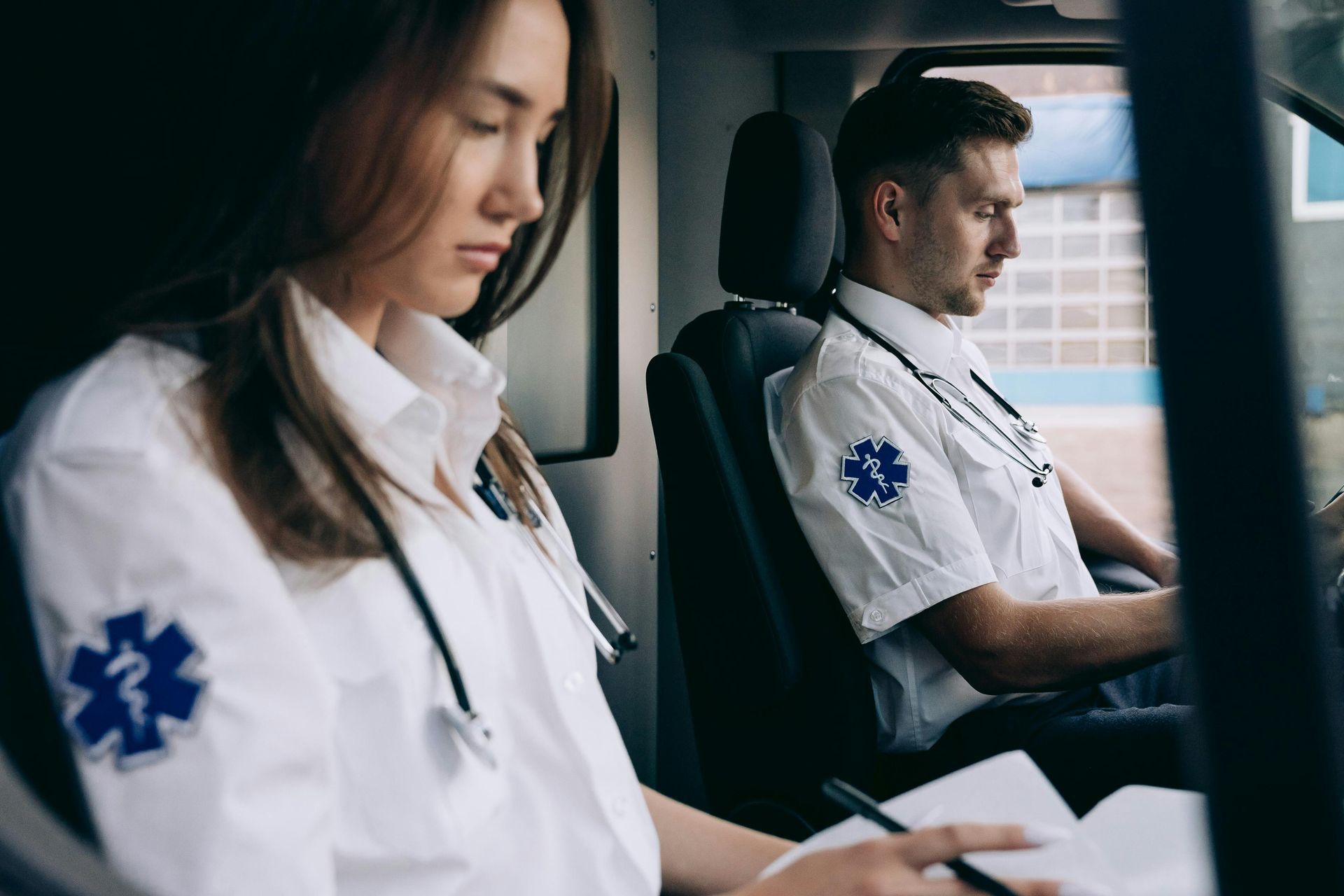 Doctor in white coat working on a laptop at a desk, typing in a bright office