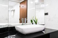 Modern bathroom with white vessel sink, black countertop, and wood cabinet mirror panel